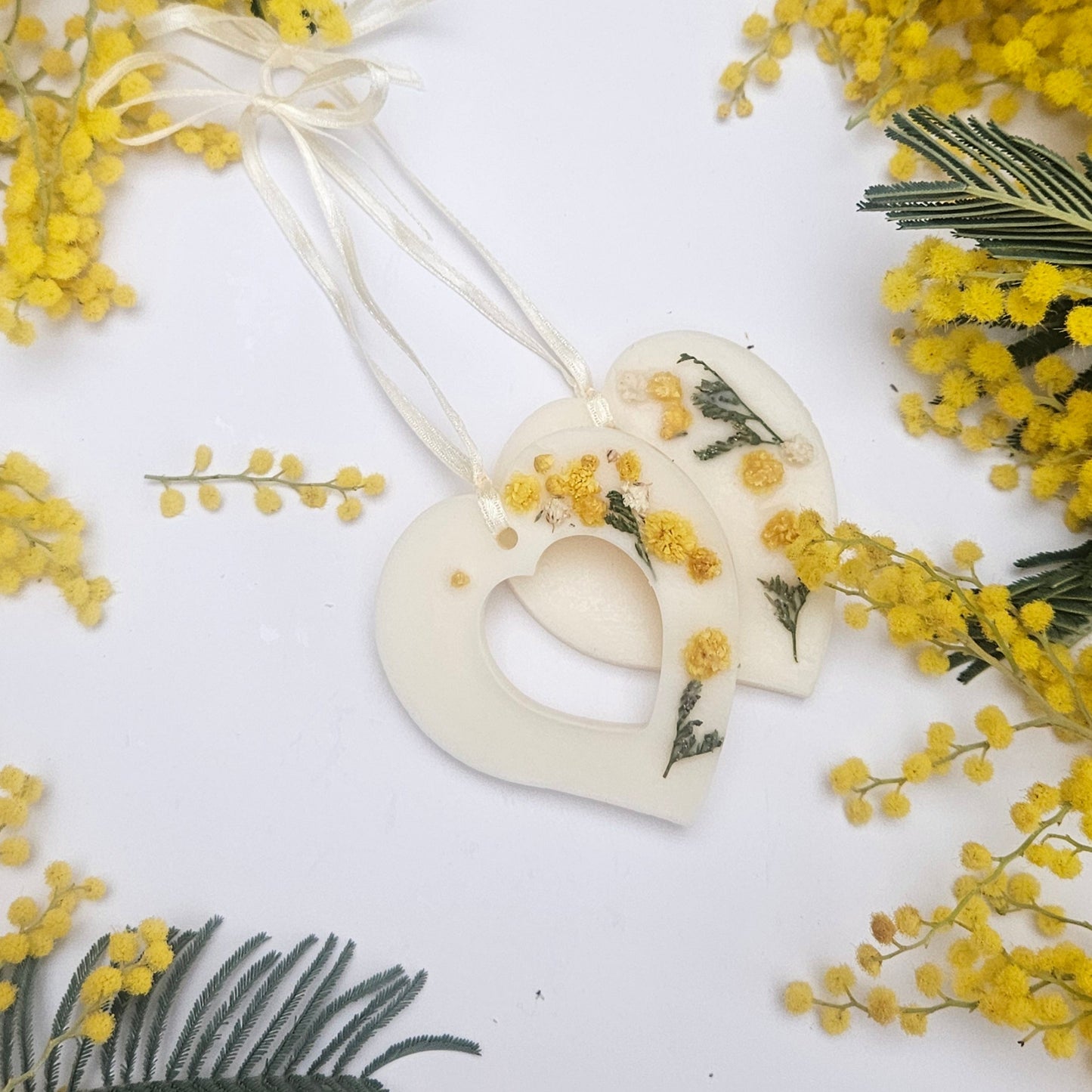 Botanical Air Freshener shaped in heart with yellow flowers and green leaves on a white background.