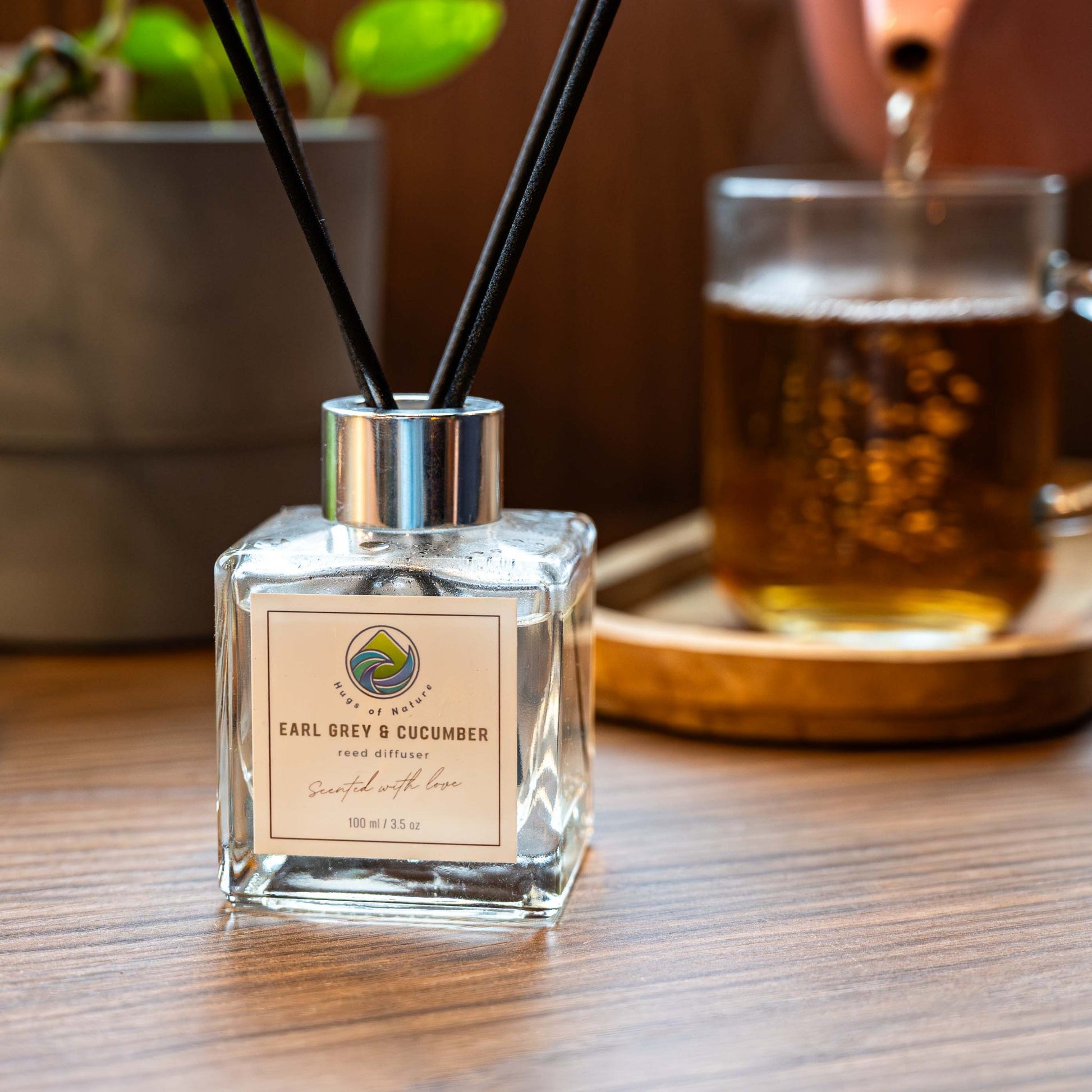 Diffuser bottle with reeds on a table next to a teacup and teapot